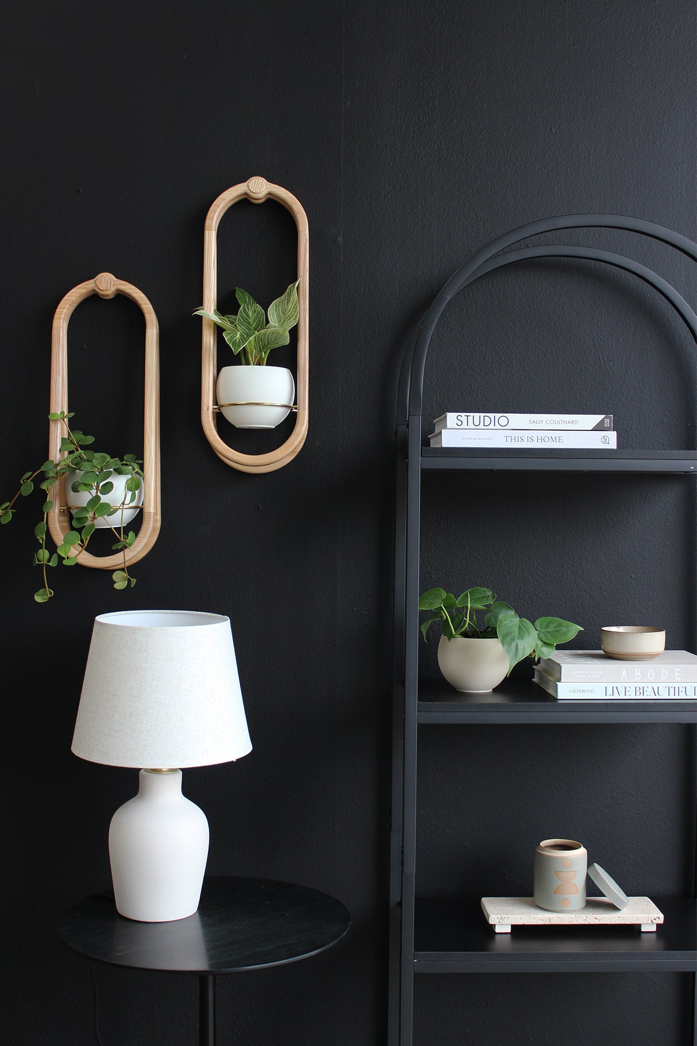 two modern solid wood wall planters with white pots above a side table with lamp